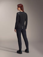 Maillot thermique pour femme Alpinestars Stella A-Dura, maillot de VTT à manches longues noir, vue arrière montrant les détails réfléchissants aux épaules et le pan arrière allongé, porté avec un pantalon et des chaussures noirs, équipement de performance pour le VTT.