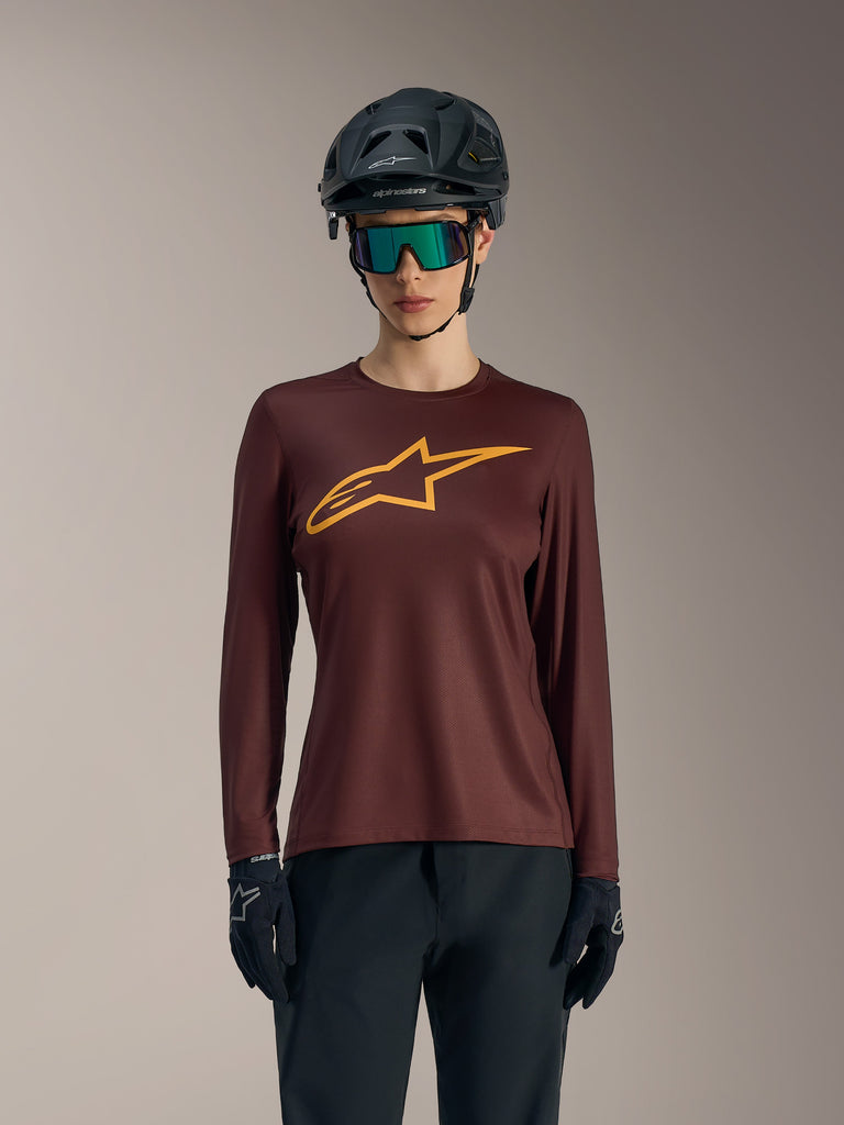 Maillot Stella A-Dura Ride femme bordeaux à manches longues, logo jaune, style VTT décontracté avec casque et lunettes.