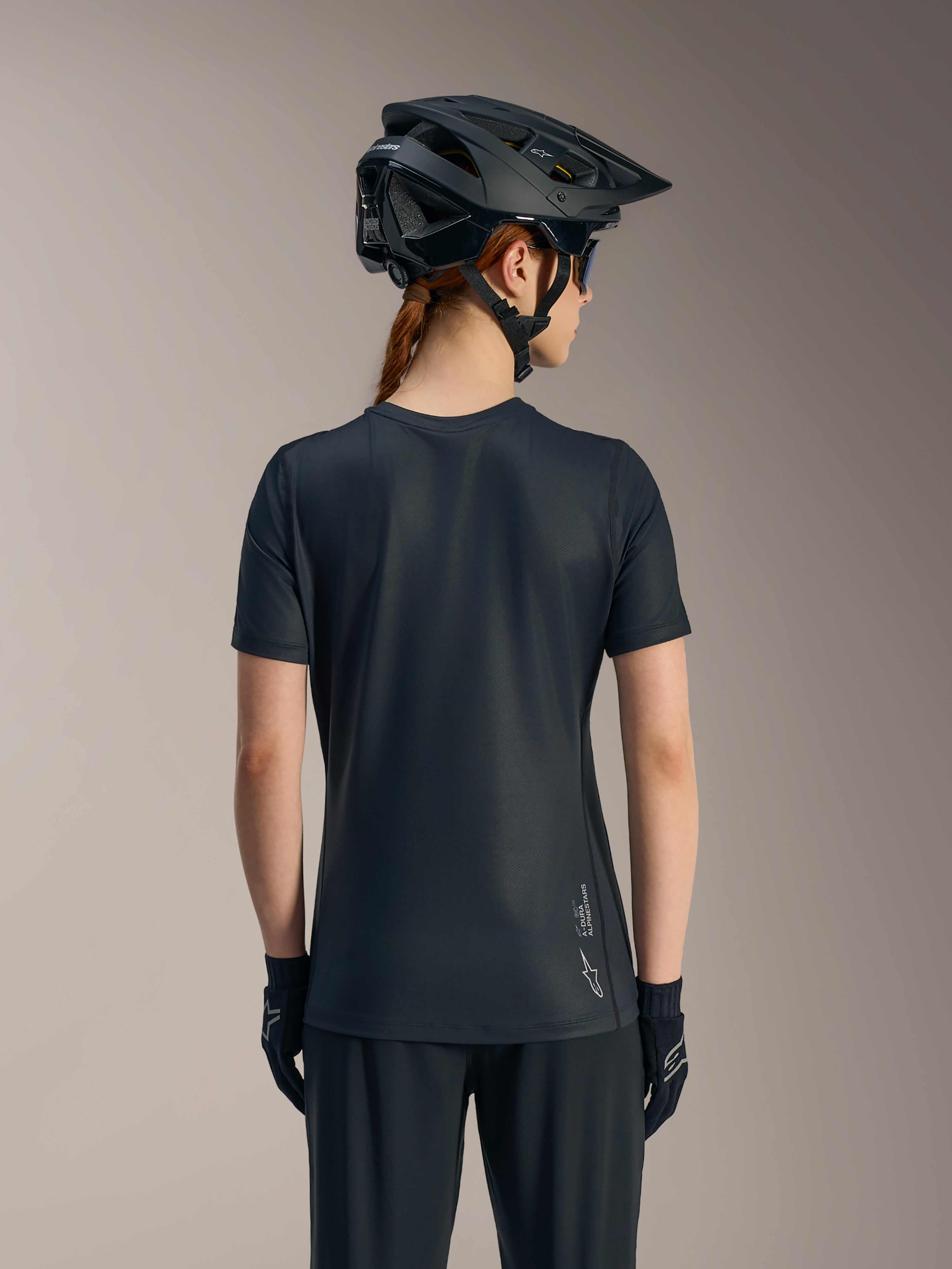 Maillot noir Stella A-Dura Ride femme à manches courtes vu de dos, avec pan arrière long et logo Alpinestars.