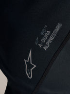 Détail du maillot VTT Stella A-Dura Ride noir, logo Alpinestars blanc et marquage A-DURA sur tissu jacquard.