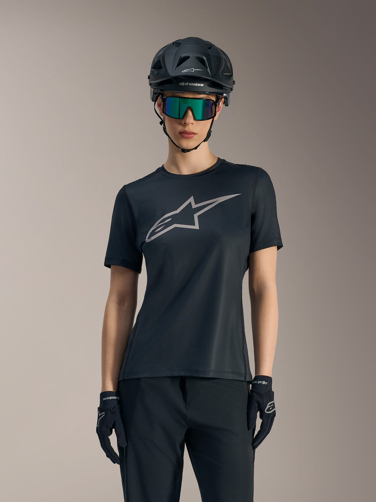 Maillot Stella A-Dura Ride noir pour femme, logo gris sur la poitrine, porté avec casque VTT et lunettes.