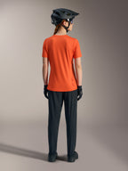 Maillot Stella A-Dura Ride Alpinestars orange pour femme, vue de dos avec pantalon de VTT noir et casque.