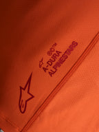 Détail du maillot orange Stella A-Dura Ride, logos Alpinestars et A-DURA sur tissu technique extensible.