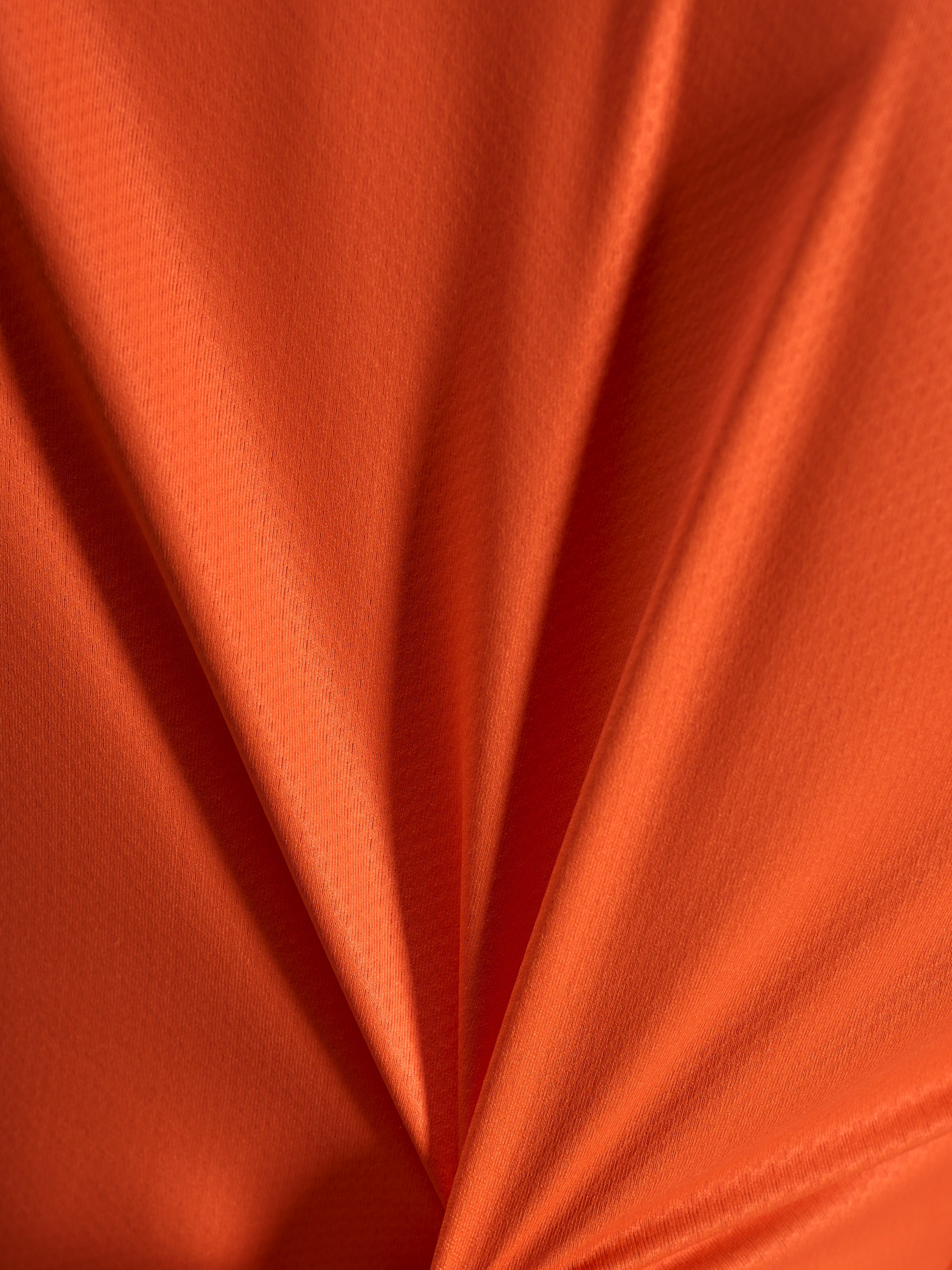 Détail du tissu jacquard orange du maillot Alpinestars Stella A-Dura Ride, texture légère et extensible.