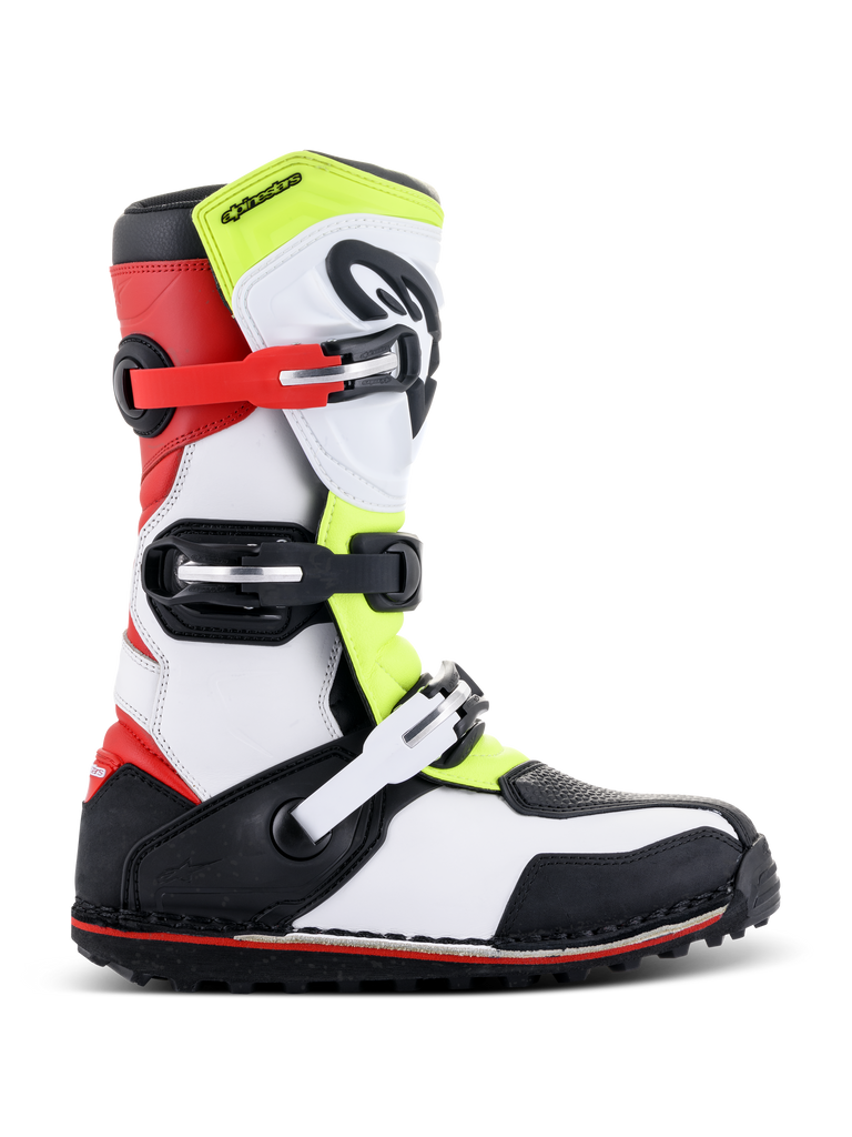 Bottes Alpinestars Tech-T, bottes de moto trial, blanc, rouge, jaune fluorescent et noir, dotées d'une plaque tibiale de protection, de boucles réglables rouges et noires et d'une semelle spécialisée pour le trial, vue de profil