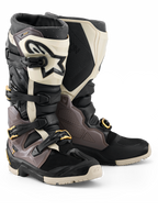 Bottes Alpinestars Tech 7 Enduro Drystar® 2026, bottes de motocross et d'enduro, noir, gris foncé et or, dotées d'une coque en TPU robuste, de boucles en aluminium à dégagement rapide avec accents dorés et d'une large plaque de tibia blanche avec logo noir, conçues pour la durabilité tout-terrain