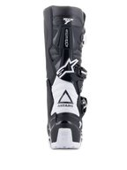 Bottes Alpinestars Tech 7 Enduro Drystar, noir et blanc, vue arrière présentant la structure de protection en TPU, les zones de flexion en accordéon blanches et le système de fermeture à boucles, avec logos Alpinestars sur le talon et la partie supérieure