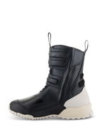 Bottes Alpinestars Stella RT-7 Touring Drystar® pour femme, noir et blanc, profil latéral d'une botte de moto de touring haute avec construction en microfibre, fermeture éclair latérale avec sangles réglables, talon et semelle blanc cassé contrastants.