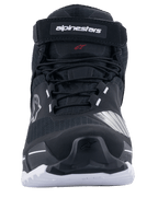 Chaussures de moto Alpinestars CR-X Drystar®, noir et blanc, vue de face montrant les lacets et la sangle supérieure avec logo Alpinestars, semelle blanche avec adhérence robuste, design inspiré des chaussures de course pour la route et l'aventure