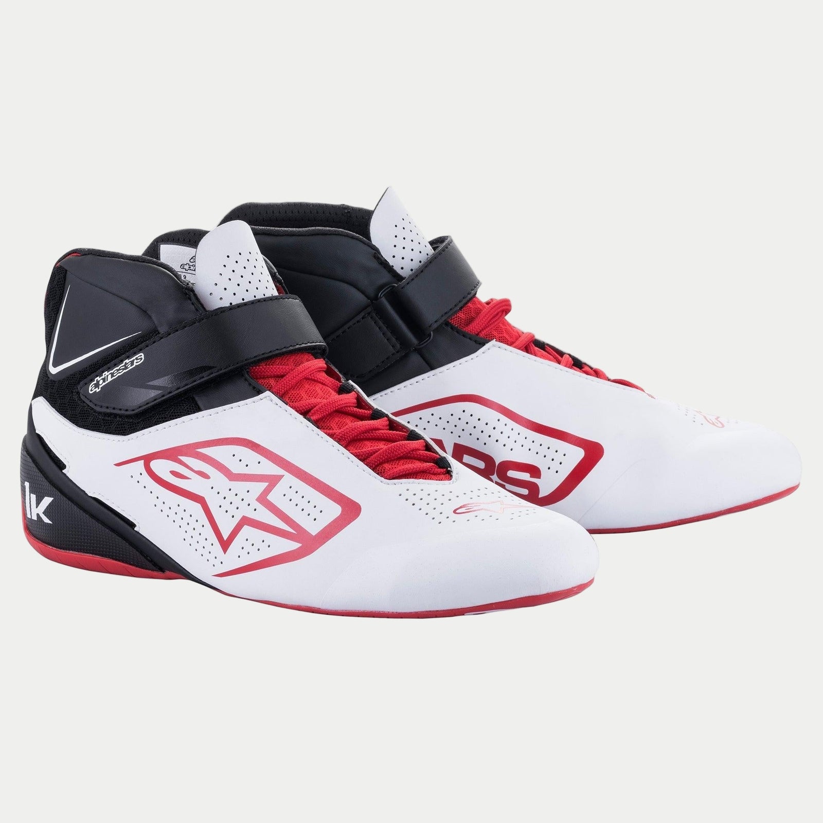 Chaussures Alpinestars Tech-1 K V2, chaussures de karting, blanc, noir et rouge, avec système de double fermeture comprenant des lacets rouges et une sangle velcro noire, panneaux perforés pour la respirabilité, logo étoile Alpinestars rouge et profil ergonomique pour la course