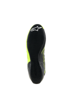 Chaussures Alpinestars Tech-1 KX V3, chaussures de karting, noir et jaune fluo, vue de dessous de la fine semelle en caoutchouc avec motif d'adhérence texturé et logo étoile blanc sur le talon, conçues pour la performance en sport automobile.