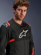 Veste Alpinestars T-Sps Air V2, noire avec des accents rouge fluo, veste de moto en textile mesh, portée par un mannequin, arborant le logo Alpinestars blanc sur la poitrine et les épaules, panneaux en mesh respirant, style urbain sportif