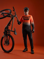 Maillot A-Dura ASTARS 2.0 manches longues, dégradé orange et noir, logo poitrine et équipement de VTT.