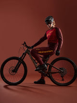Maillot bordeaux A-Dura Elite 2.0 et pantalon assorti Alpinestars portés par un vététiste sur vélo Specialized en studio.
