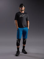 Maillot Alpinestars A-Dura Ride SS noir et short bleu, tenue de VTT complète avec protections et casque.