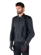 Pilote portant la veste en cuir Alpinestars Missile V3 en noir, en cuir bovin premium avec panneaux de poitrine perforés et protections d'épaules externes DFS, associée à un pantalon noir et des gants de course noirs et rouges.