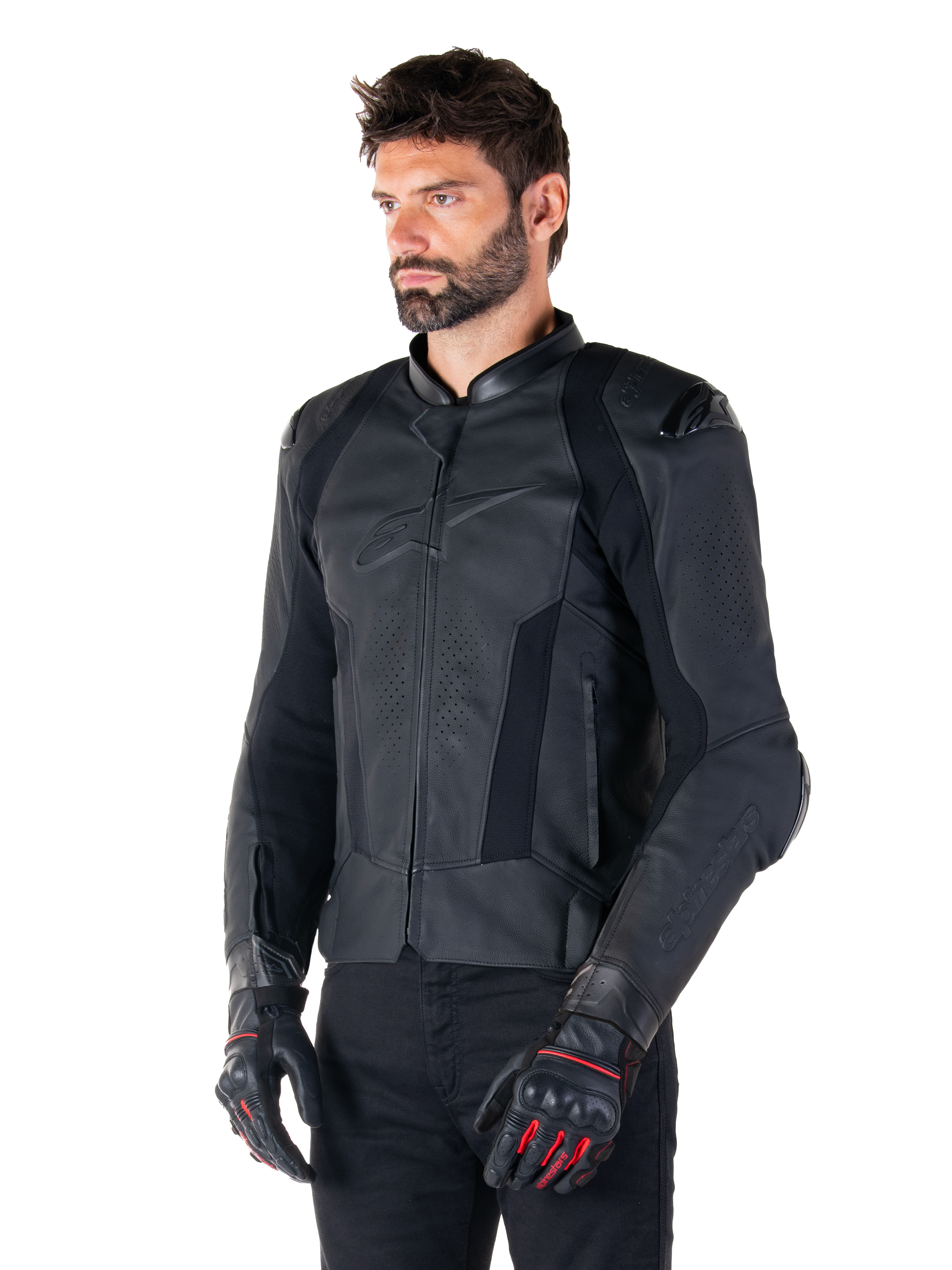 Pilote portant la veste en cuir Alpinestars Missile V3 en noir, en cuir bovin premium avec panneaux de poitrine perforés et protections d'épaules externes DFS, associée à un pantalon noir et des gants de course noirs et rouges.