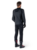 Veste en cuir Alpinestars Missile V3 noire, vue arrière sur un motard, portée avec un pantalon noir et des bottes de course noires et rouges, dotée d'une construction en cuir élégante avec un marquage ton sur ton et une coupe racing performante