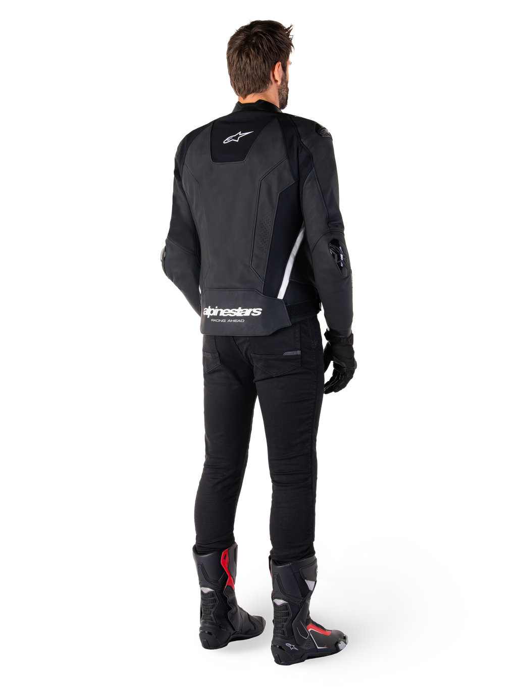 Veste en cuir Alpinestars Missile V3, noir et blanc, vue arrière sur le pilote, avec logo Alpinestars blanc imposant en bas du dos et petit logo sur le haut du dos, portée avec un pantalon noir et des bottes de course, conception en cuir premium pour la course moto