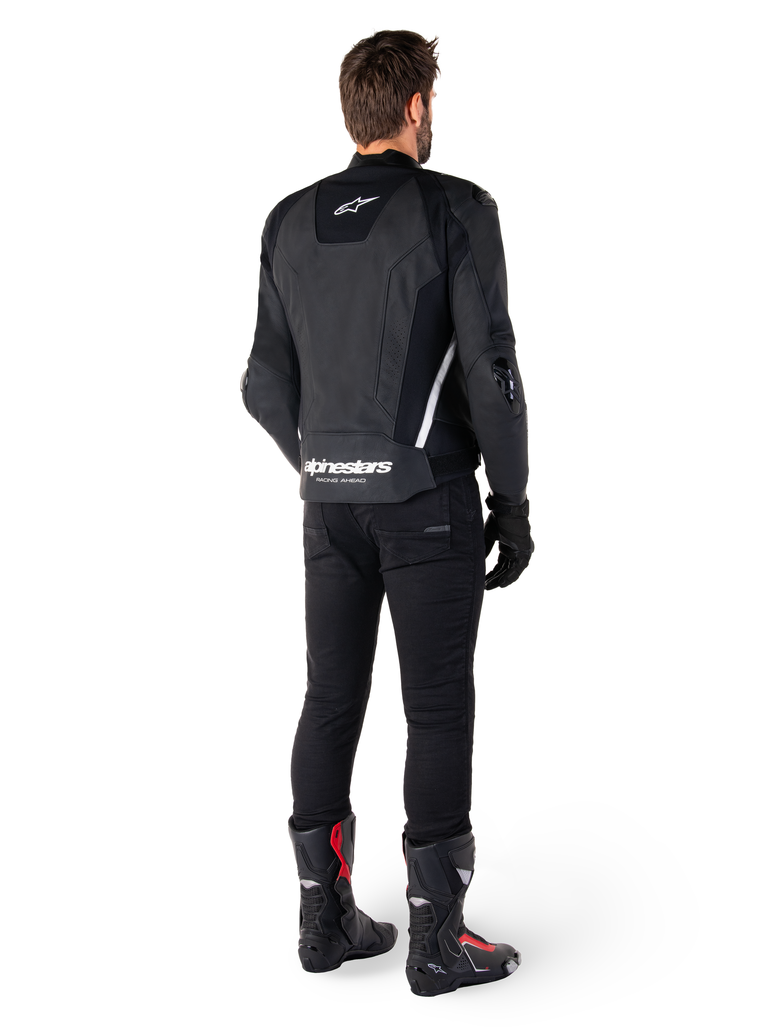Veste en cuir Alpinestars Missile V3, noir et blanc, vue arrière sur le pilote, avec logo Alpinestars blanc imposant en bas du dos et petit logo sur le haut du dos, portée avec un pantalon noir et des bottes de course, conception en cuir premium pour la course moto