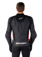 Veste en cuir Alpinestars Missile V3, vue de dos, cuir noir premium avec accents rouge fluo et blancs, arborant un logo étoile blanche sur le haut du dos et le logo Alpinestars sur le bas du dos, portée avec un pantalon et des gants noirs