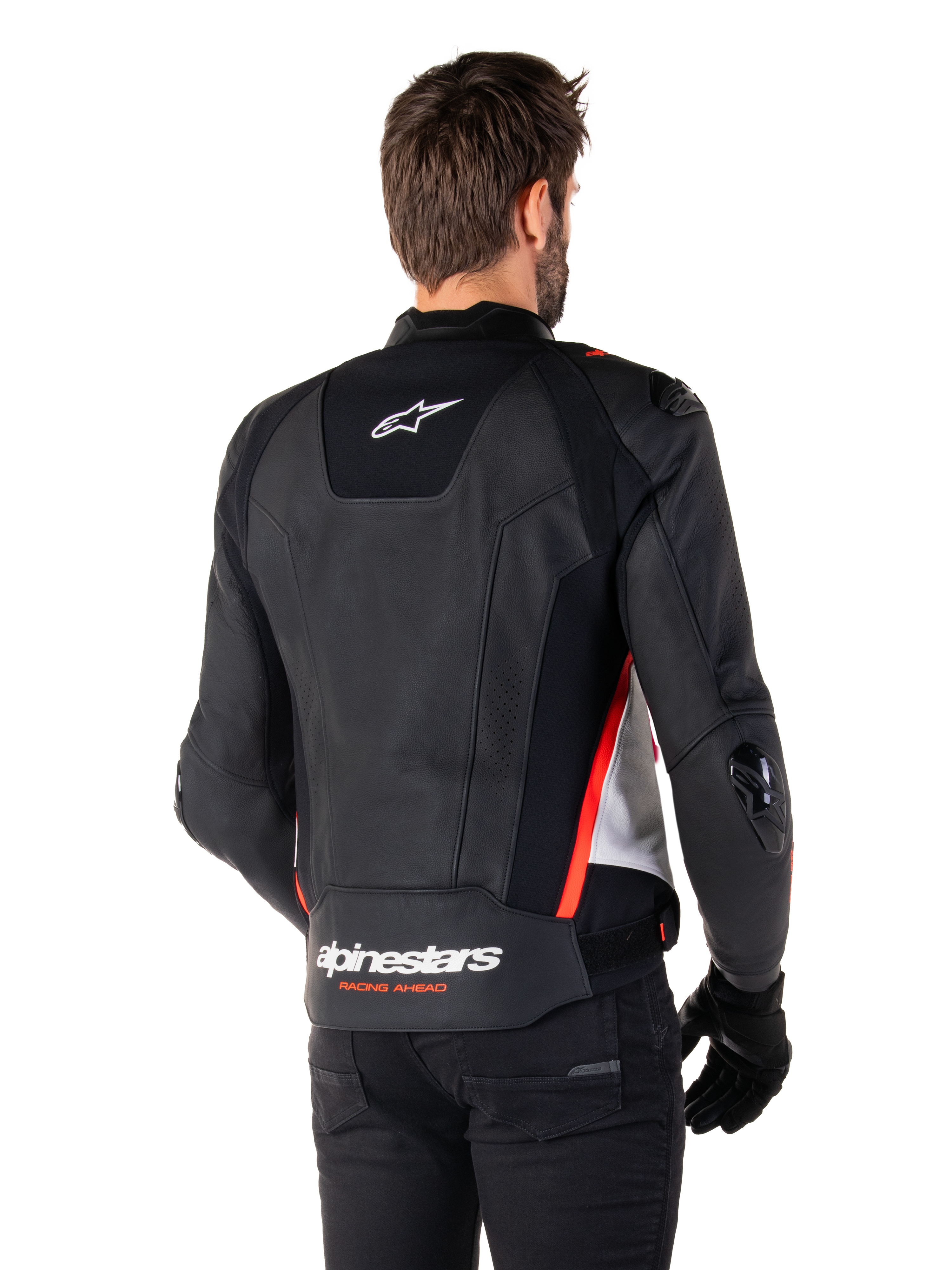 Veste en cuir Alpinestars Missile V3, vue de dos sur un motard, noir, blanc et rouge fluo, avec logo Alpinestars et texte « RACING AHEAD » au bas du dos, construction en cuir premium avec panneaux extensibles techniques et sliders de protection en TPU, portée avec des gants et un pantalon noirs.