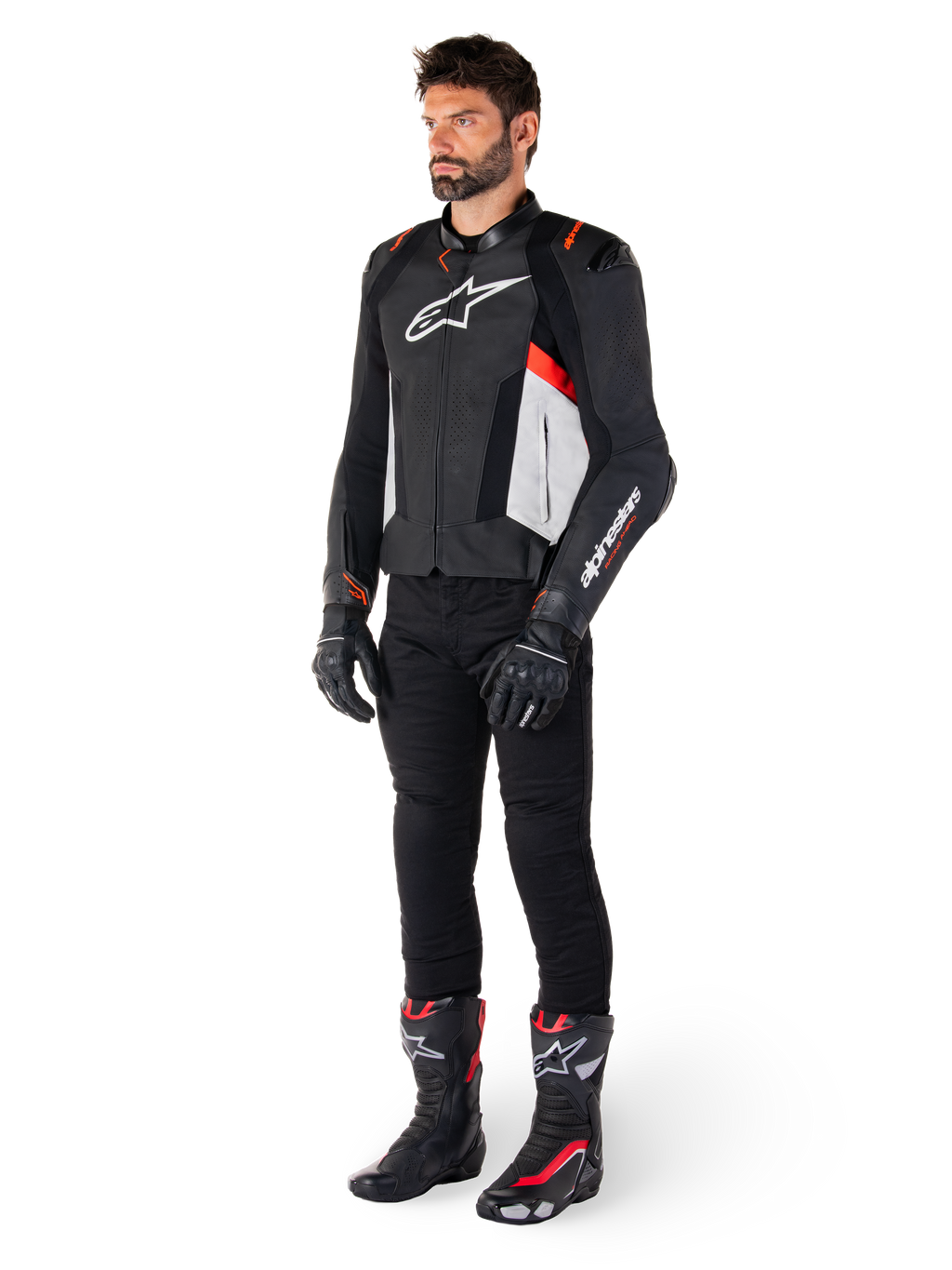 Modèle masculin portant la veste en cuir Alpinestars Missile V3 en Noir, Blanc et Rouge Fluo, avec pantalon, gants et bottes de moto noirs, construction en cuir de bovin haut de gamme, logos Alpinestars distinctifs, esthétique de course professionnelle