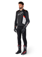 Modèle masculin portant la veste en cuir Alpinestars Missile V3 en Noir, Blanc et Rouge Fluo, avec pantalon, gants et bottes de moto noirs, construction en cuir de bovin haut de gamme, logos Alpinestars distinctifs, esthétique de course professionnelle