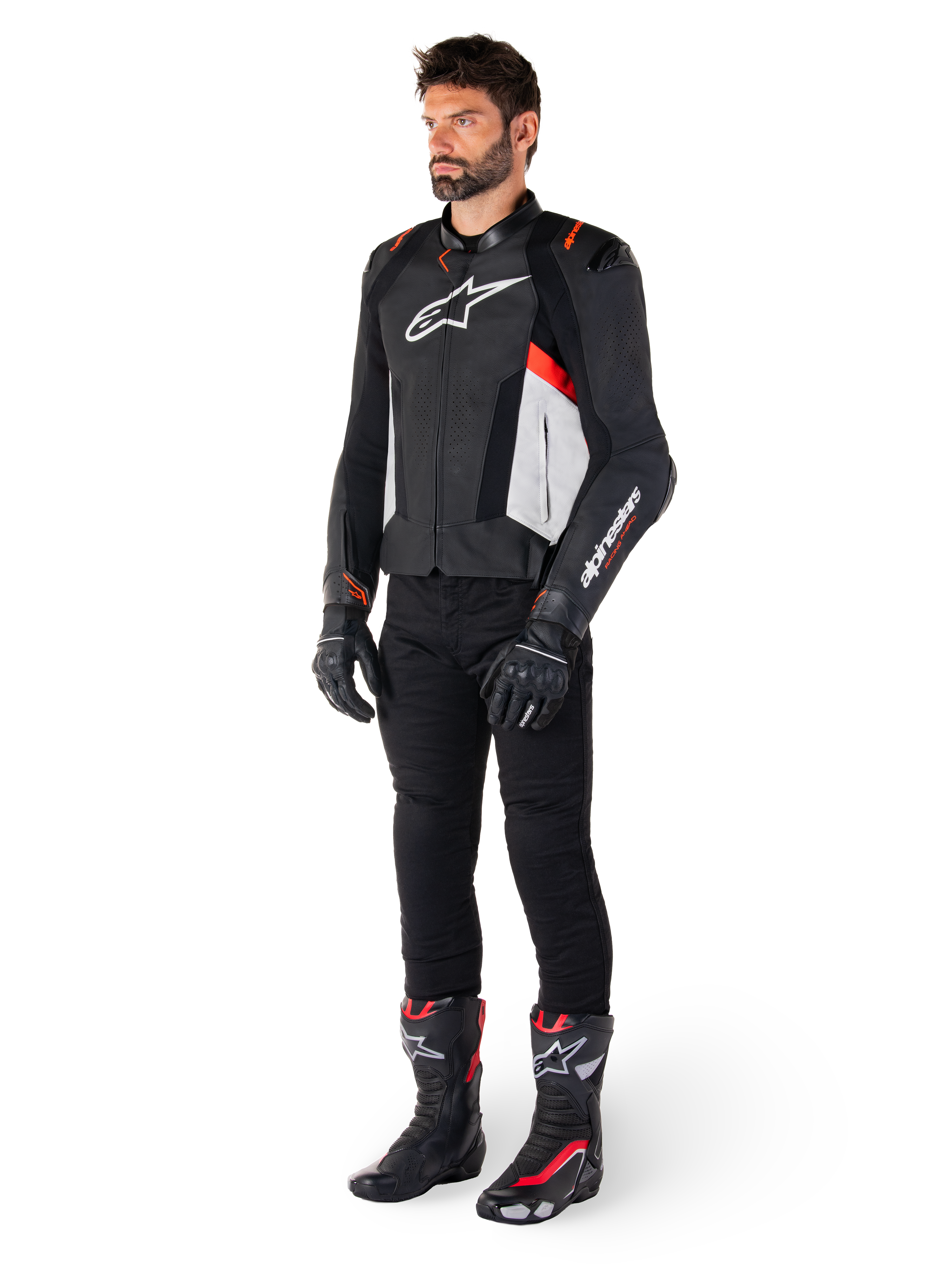Modèle masculin portant la veste en cuir Alpinestars Missile V3 en Noir, Blanc et Rouge Fluo, avec pantalon, gants et bottes de moto noirs, construction en cuir de bovin haut de gamme, logos Alpinestars distinctifs, esthétique de course professionnelle