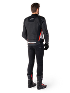 Veste en cuir Alpinestars Missile V3 en Noir Blanc Rouge Fluo, vue de dos sur un motard, arborant le logo Alpinestars sur le haut et le bas du dos, associée à un pantalon noir et des bottes de moto, veste de sport en cuir inspirée de la course