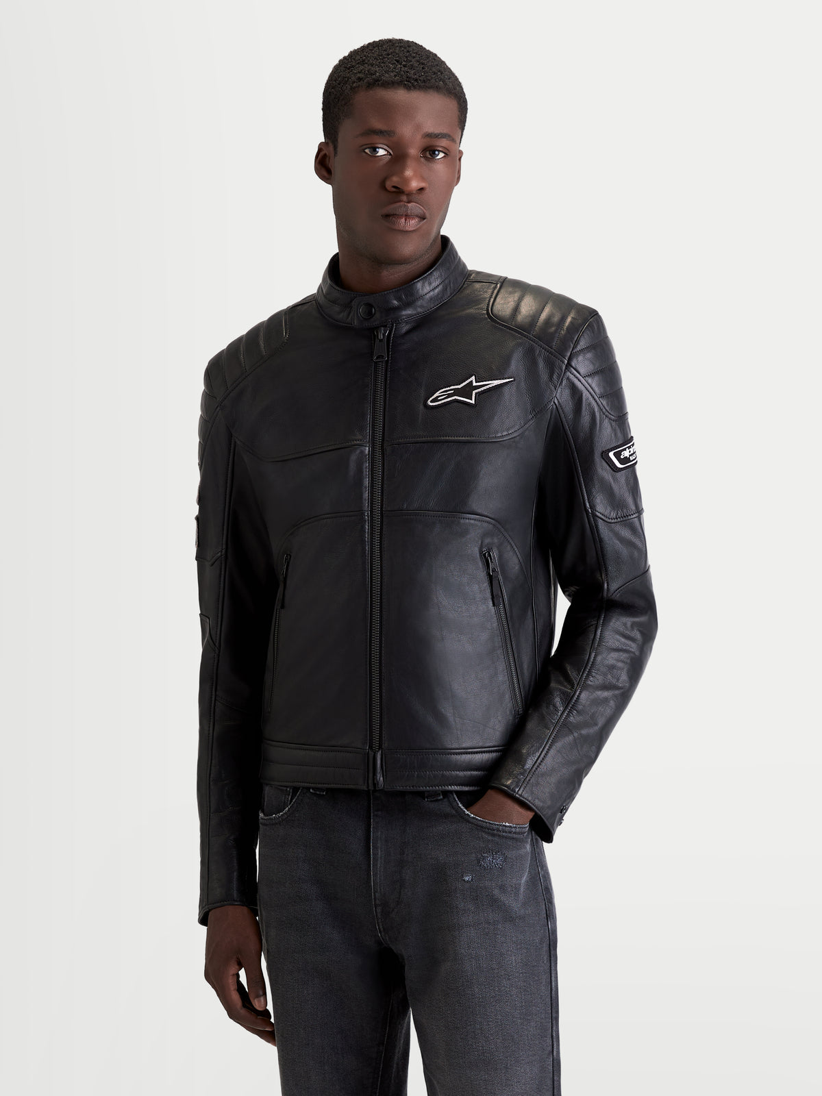 Alpinestars Revern Leather Jacket, men's urban motorcycle leather jacket in black, front view on a model wearing heritage road apparel with certified shoulder and elbow protection.