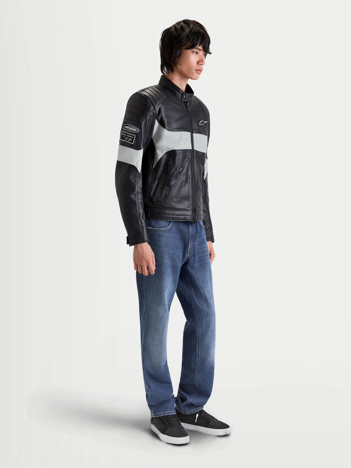 Veste en cuir Revern d'Alpinestars, blouson de moto urbain pour homme noir et gris métal, vue de profil par un modèle portant un jean, avec une construction en cuir pleine fleur vieilli et un style héritage