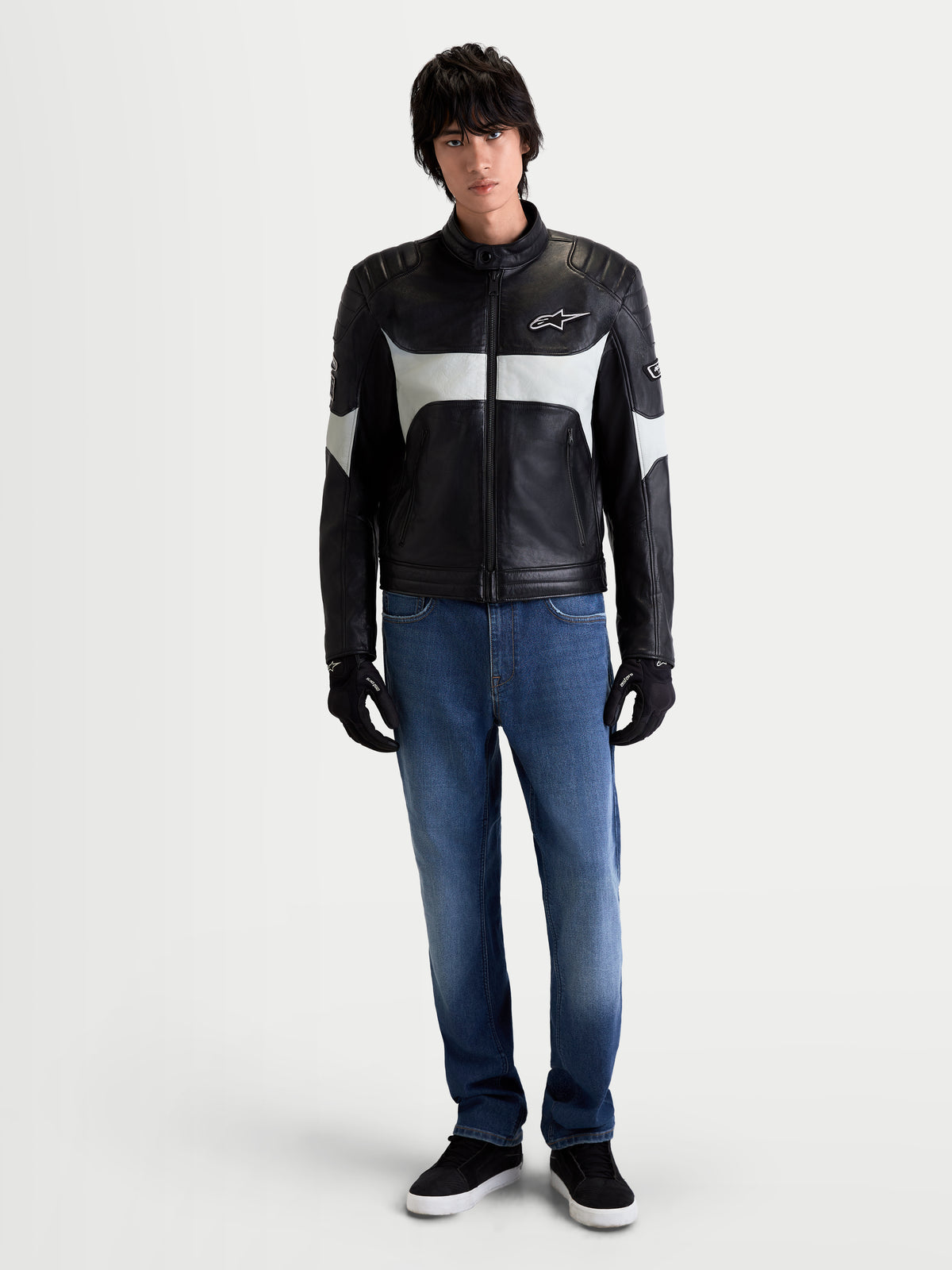 Alpinestars Revern Veste en cuir, veste moto urbaine pour homme noire et gris métal, vue de face sur un modèle portant un jean et des gants noirs, mettant en valeur son style rétro et sa construction en cuir de bovin pleine fleur
