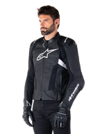 Homme portant la veste en cuir Alpinestars Missile V3 Airflow, veste de moto noire et blanche, cuir perforé premium pour une circulation d'air optimale, logo Alpinestars blanc sur la poitrine et la manche, coupe sportive inspirée de la course, portée avec des gants et un pantalon noirs