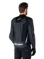 Veste en cuir Alpinestars Missile V3 Airflow, noir et blanc, vue arrière avec cuir perforé et panneaux en mesh pour une ventilation maximale, logo Alpinestars blanc sur le bas du dos et logo étoile sur le col, portée avec un équipement de moto noir, design sportif haut de gamme.
