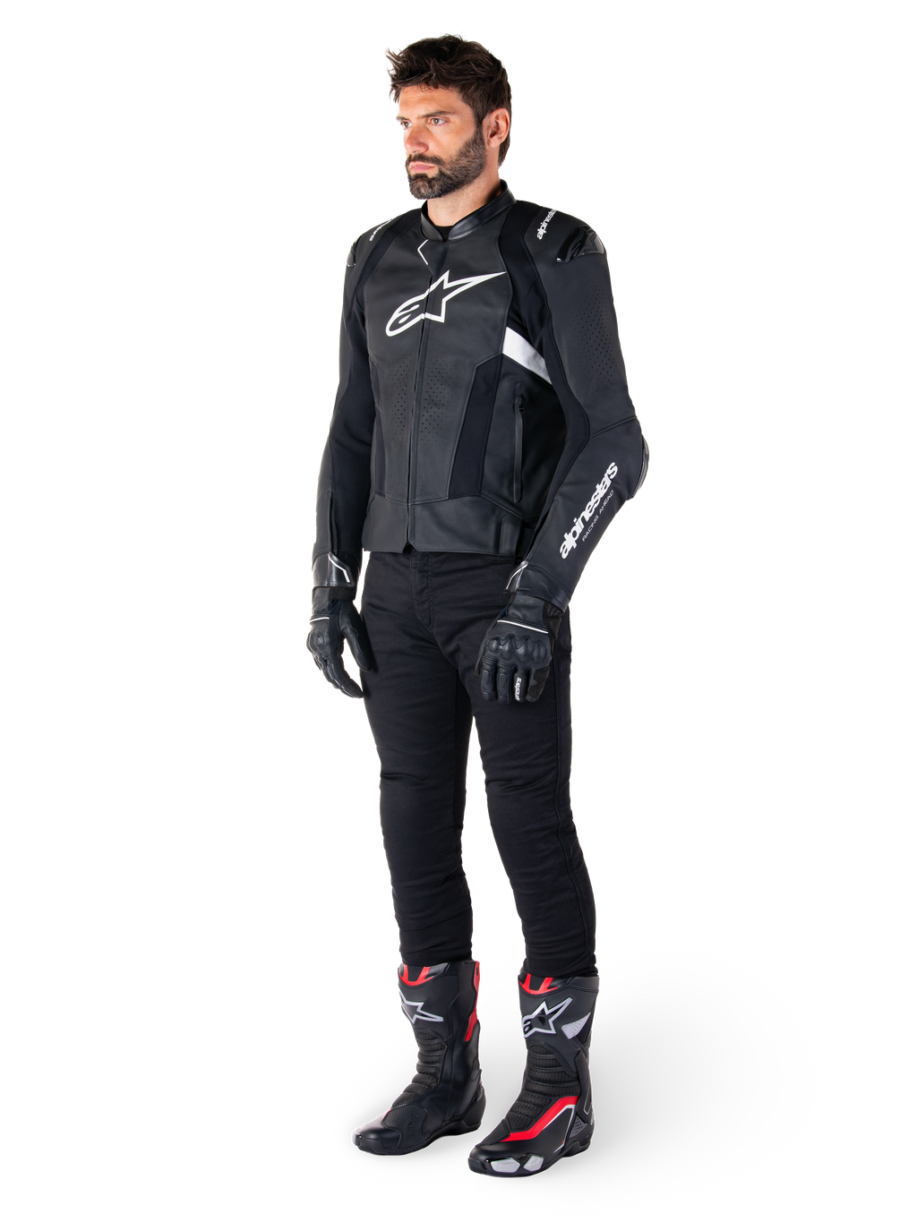 Veste en cuir Alpinestars Missile V3 Airflow, noir et blanc, portée par un mannequin homme avec un pantalon de moto noir, des gants noirs et des bottes de course avec des accents rouges et blancs, dotée de cuir perforé et de logos blancs, équipement de course de moto haute performance