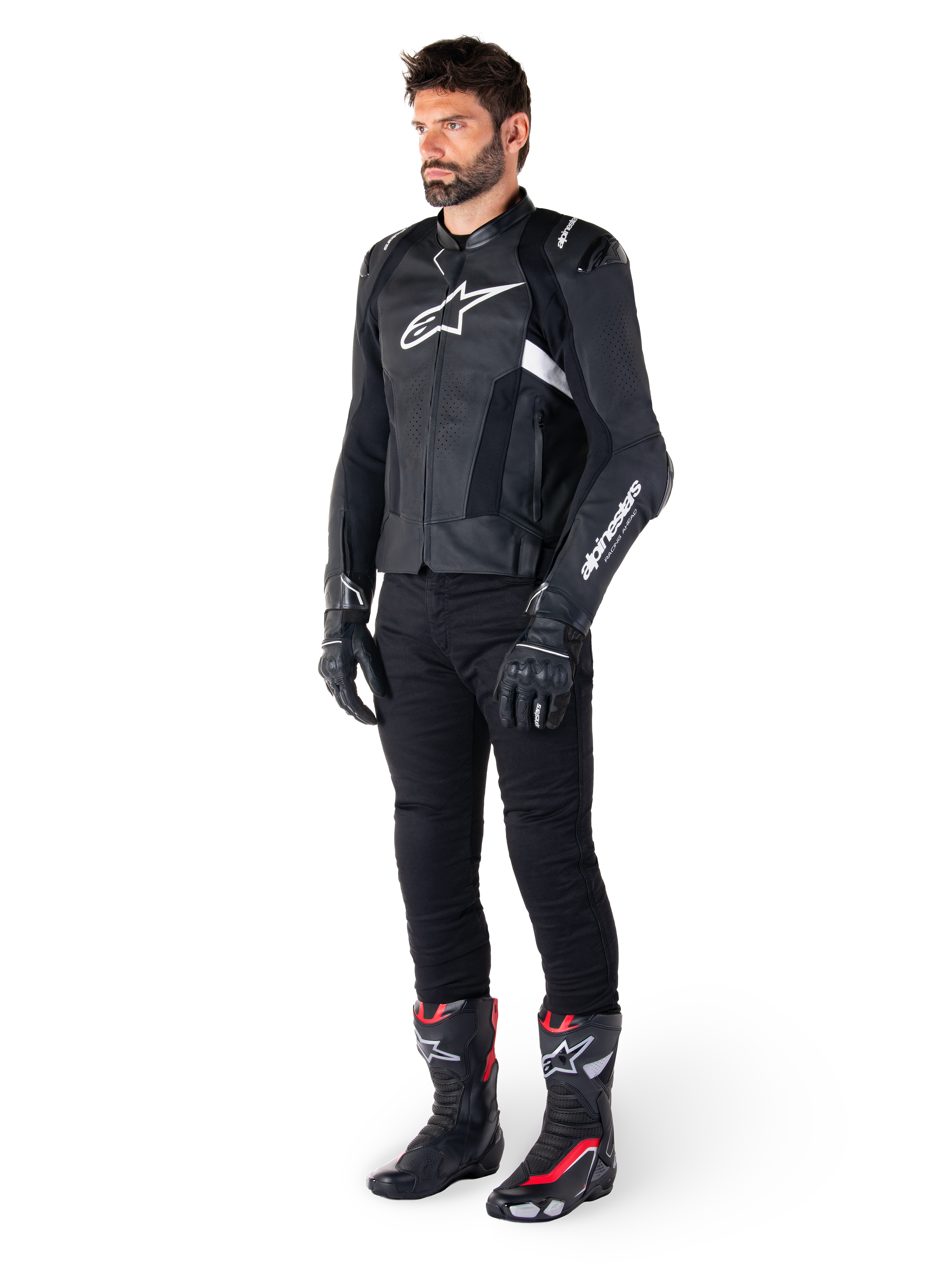 Veste en cuir Alpinestars Missile V3 Airflow, noir et blanc, portée par un mannequin homme avec un pantalon de moto noir, des gants noirs et des bottes de course avec des accents rouges et blancs, dotée de cuir perforé et de logos blancs, équipement de course de moto haute performance
