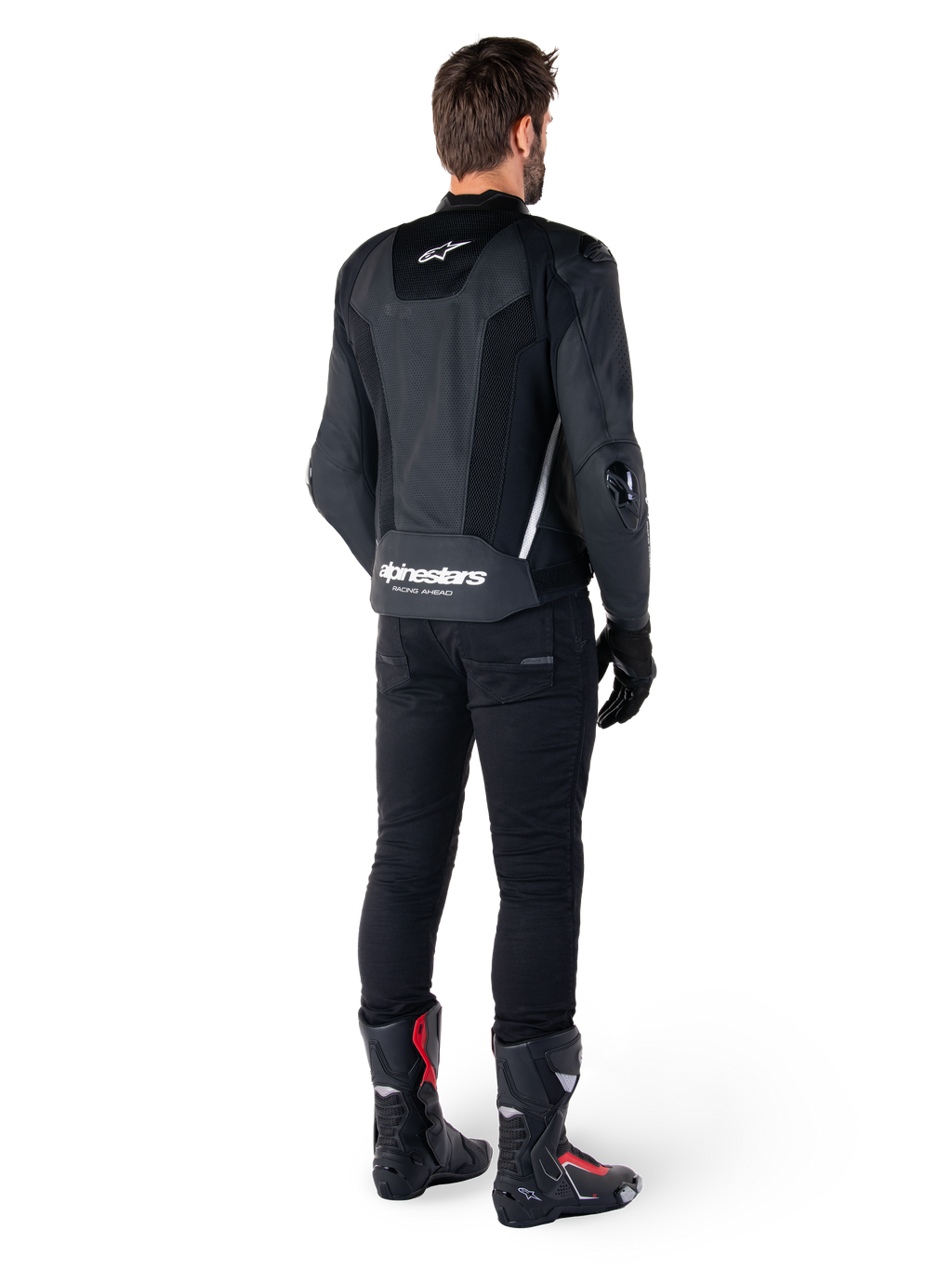 Veste en cuir Alpinestars Missile V3 Airflow, noir et blanc, vue de dos avec pantalon technique noir et bottes de course, panneaux arrière en cuir perforé et logo Alpinestars distinctif sur le bas du dos.