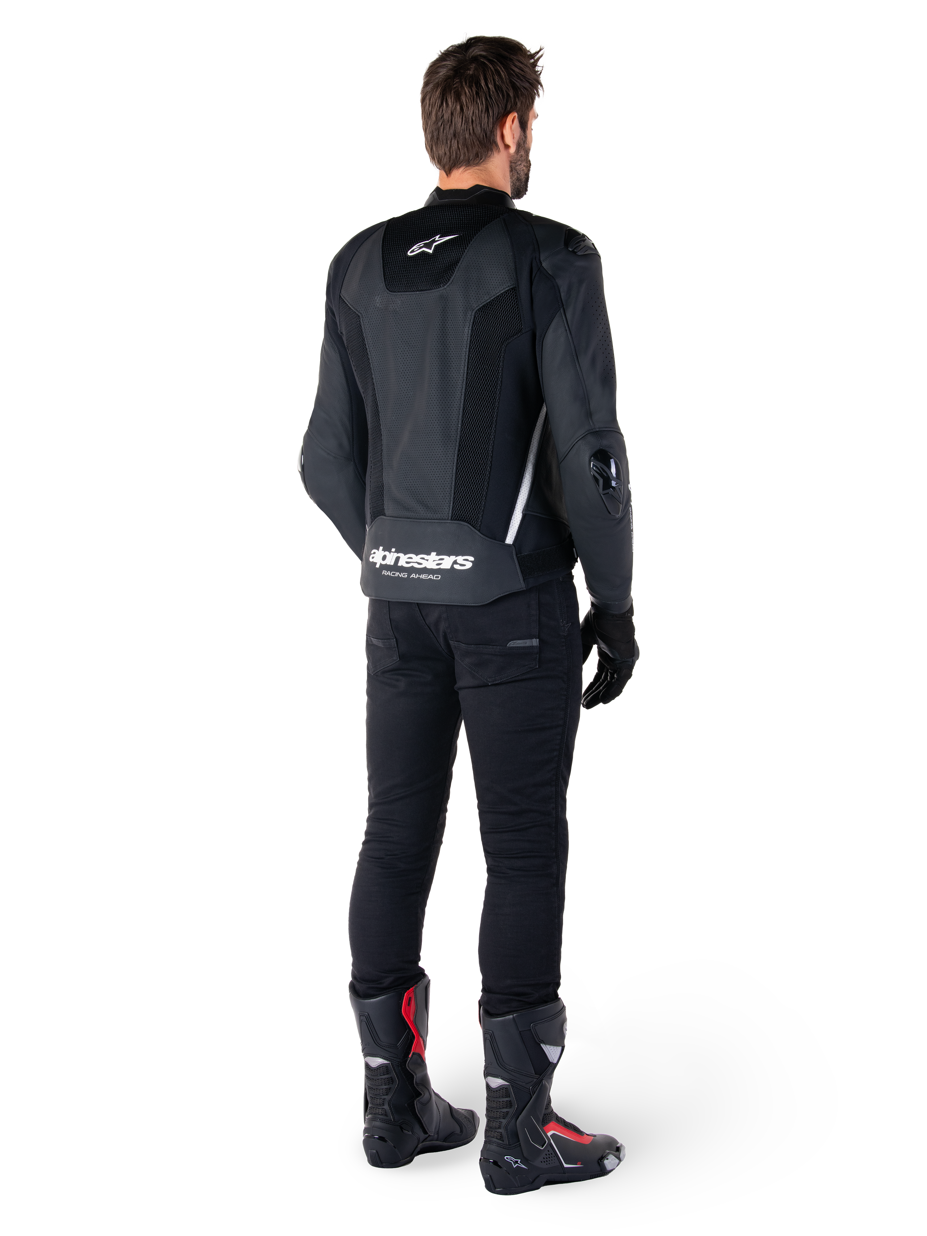 Veste en cuir Alpinestars Missile V3 Airflow, noir et blanc, vue de dos avec pantalon technique noir et bottes de course, panneaux arrière en cuir perforé et logo Alpinestars distinctif sur le bas du dos.