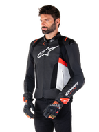 Veste en cuir Alpinestars Missile V3 Airflow, noir, blanc et rouge fluo, veste de moto racing sport, portée par un mannequin avec des gants assortis, avec panneaux en cuir perforé, grand logo blanc sur la poitrine et sliders d'épaule noirs.