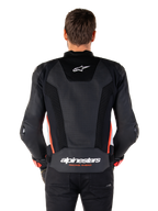 Vue arrière d'une personne portant la veste en cuir Alpinestars Missile V3 Airflow en Noir Blanc Rouge Fluo, dotée de larges panneaux en cuir perforé pour la ventilation, d'un petit logo Alpinestars sur le haut du dos et d'un marquage « alpinestars RACING AHEAD » imposant au bas de la taille.