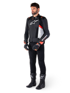 Veste en cuir Alpinestars Missile V3 Airflow, noir, blanc et rouge fluo, portée par un mannequin homme avec un pantalon noir, des gants de course noirs et des bottes noires, dotée de cuir perforé pour la ventilation, un logo blanc sur la poitrine et des accents rouge fluo, conçue pour une performance de course et de sport haut de gamme.