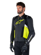 Modèle masculin portant la veste en cuir Alpinestars Missile V3 Airflow, noir avec détails jaune fluo et blancs, cuir perforé pour une ventilation maximale, logo jaune vif sur la poitrine, avec gants et pantalon noirs, équipement de moto racing de style sportif
