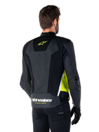 Veste en cuir Alpinestars Missile V3 Airflow, vue arrière sur un mannequin masculin, noire avec accents jaune fluo et blancs, dotée de larges panneaux en cuir perforé et en mesh sur le dos, arborant un logo étoile jaune et le texte blanc 'RACING AHEAD', accompagnée de gants et d'un pantalon noirs.