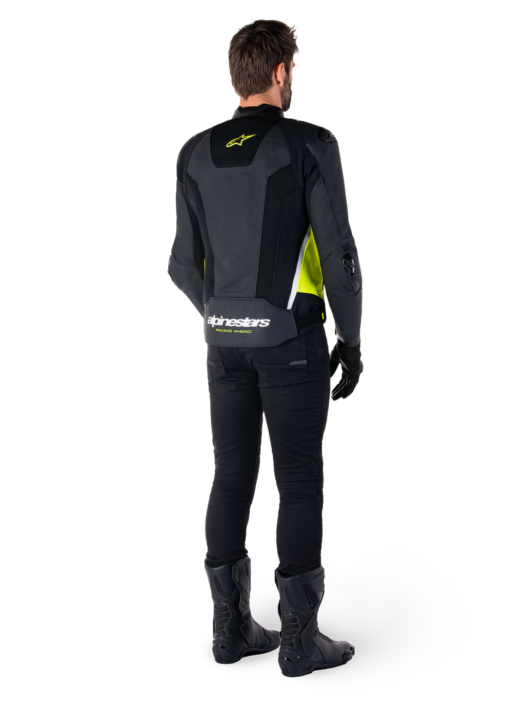 Veste en cuir Alpinestars Missile V3 Airflow, noir, jaune fluo et blanc, vue de dos sur le pilote, avec panneaux arrière en cuir perforé, logo Alpinestars jaune et détails blancs, portée avec un pantalon et des bottes de moto noirs