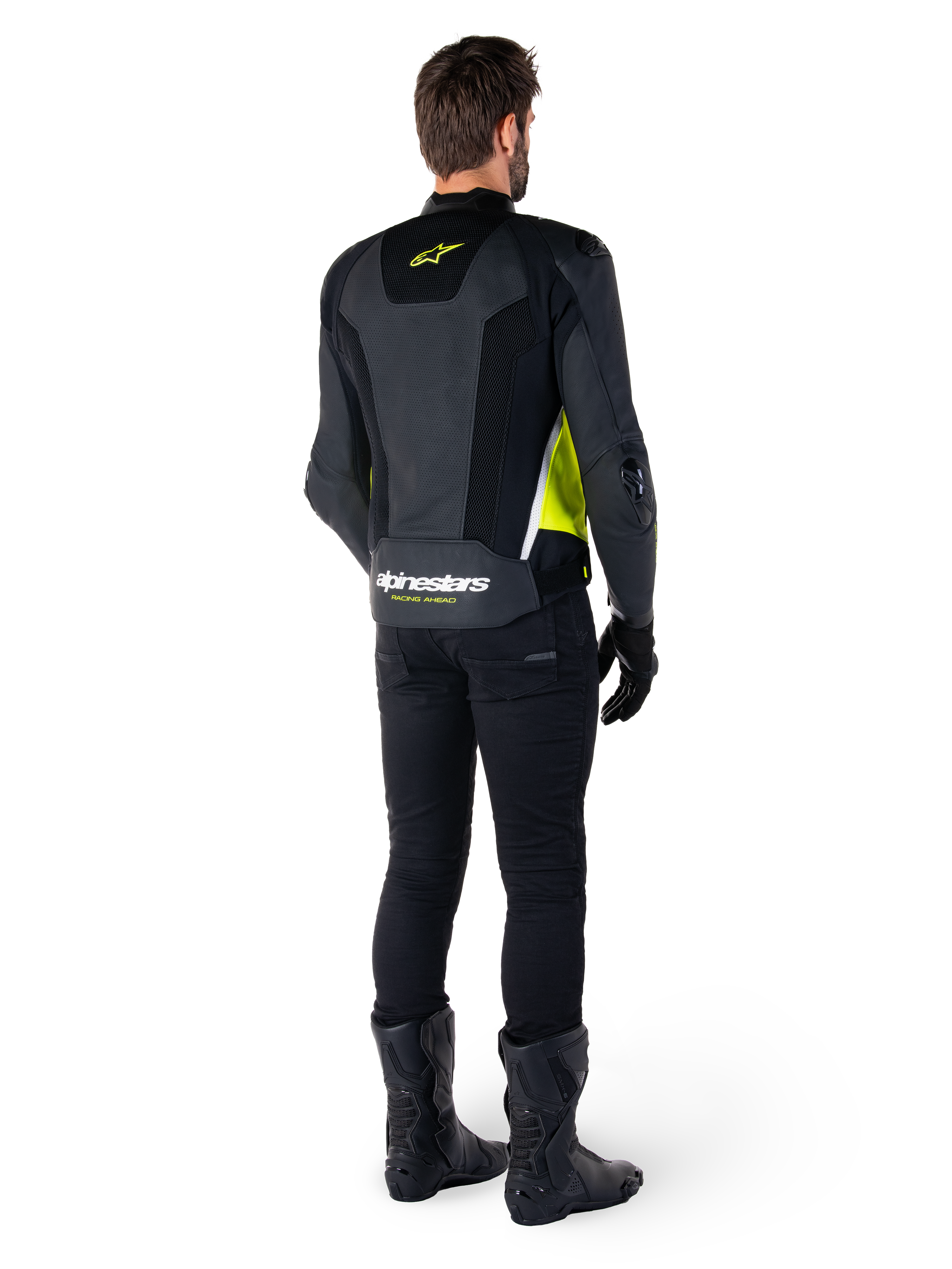 Veste en cuir Alpinestars Missile V3 Airflow, noir, jaune fluo et blanc, vue de dos sur le pilote, avec panneaux arrière en cuir perforé, logo Alpinestars jaune et détails blancs, portée avec un pantalon et des bottes de moto noirs