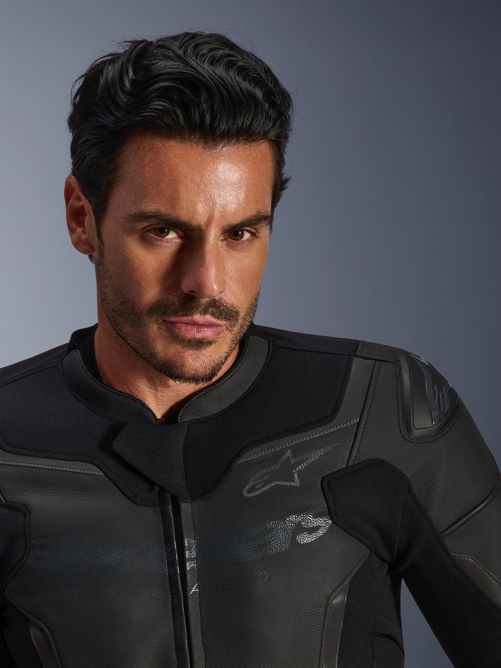 Portrait en gros plan d'un mannequin portant la veste en cuir Alpinestars GP Force V2 noire, dotée d'une construction en cuir bovin de qualité supérieure, de panneaux extensibles en textile et d'un logo étoile Alpinestars discret, au design épuré axé sur le sport pour la conduite sur route.