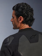 Veste en cuir Alpinestars GP Force V2, noire, vue rapprochée de l'arrière, présentant le logo étoile noir sur le haut du dos et la protection d'épaule GP Lite Evo DFS, construction multi-panneaux en cuir et textile, vue en studio du profil du pilote et des détails de l'équipement.