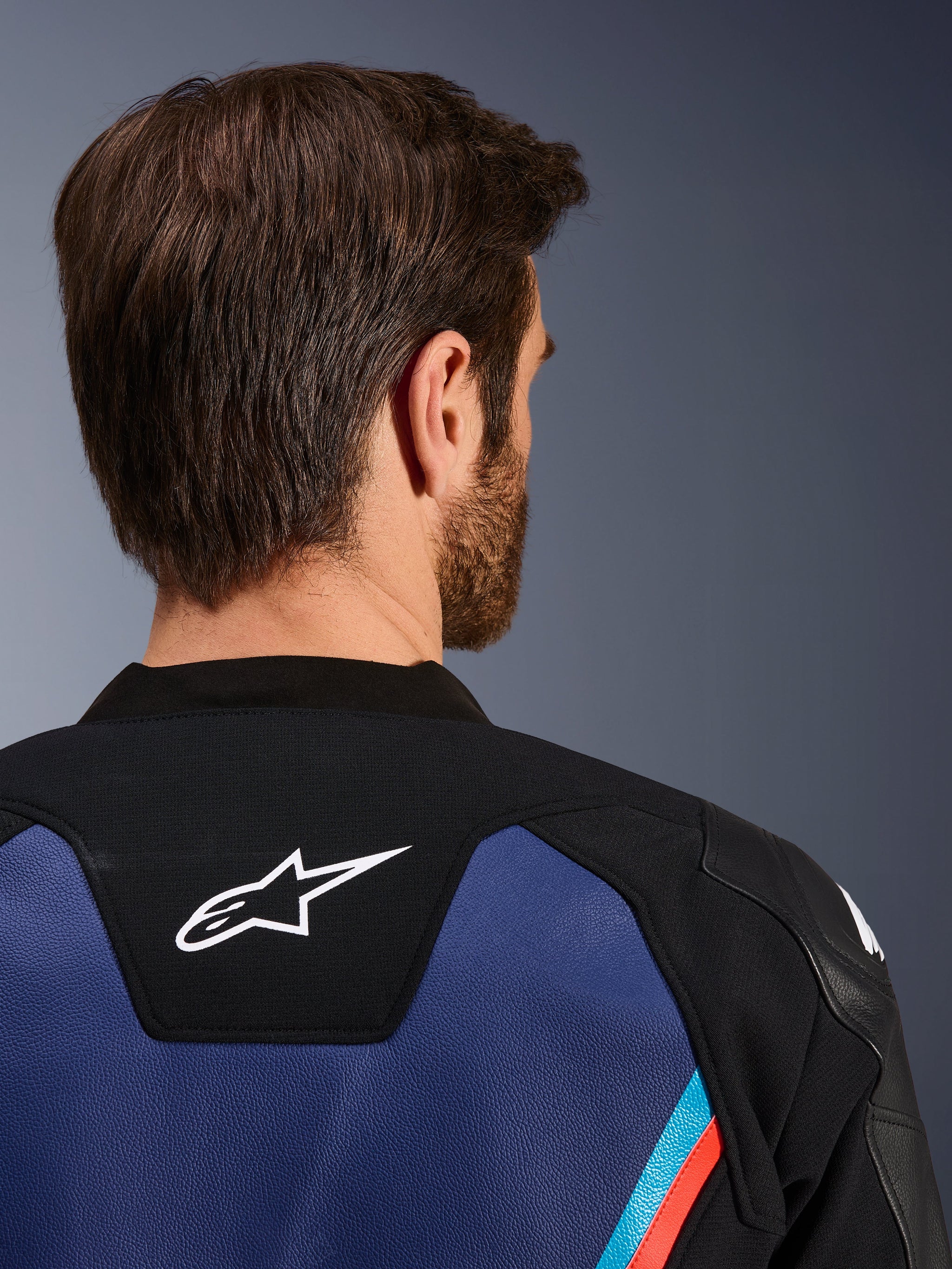 Blouson en cuir Alpinestars GP Force V2, vue arrière rapprochée du cou et des épaules, logo Astars blanc sur empiècement noir, cuir bleu avec accents rouge fluo et bleu clair, équipement de sport moto