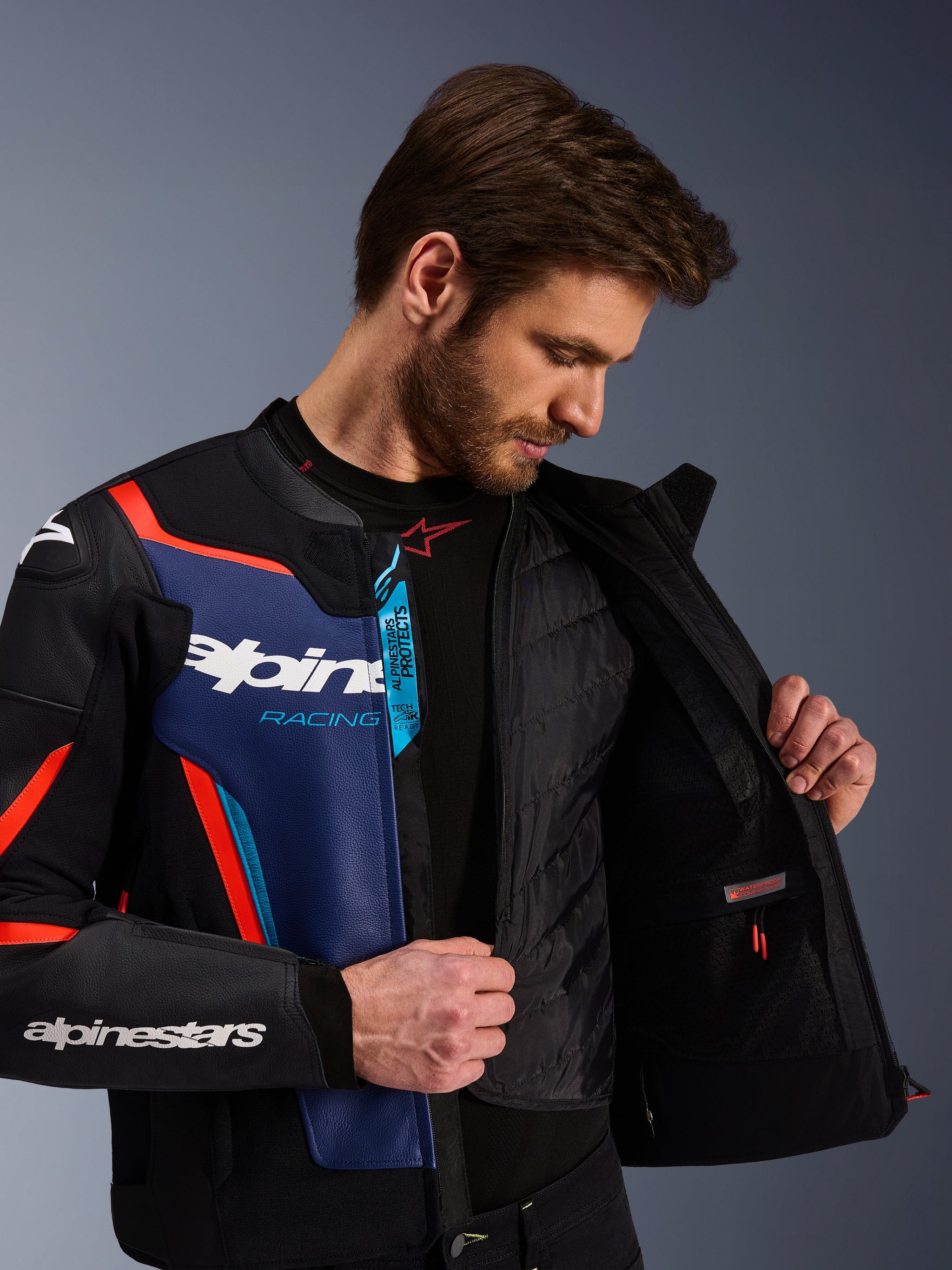 Blouson en cuir Alpinestars GP Force V2 en Noir Bleu et Rouge Fluo, vue rapprochée montrant le gilet thermique amovible interne et la poche imperméable, cuir bovin de qualité supérieure avec marquage Tech-Air Ready, vêtement de moto optimisé pour le sport
